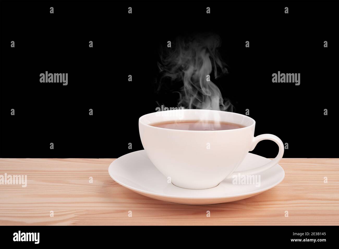 tasse blanche avec thé chaud sur table en bois isolée sur fond noir. vue latérale. Tasse chinoise blanche en porcelaine de thé noir et soucoupe sur bois d'époque Banque D'Images
