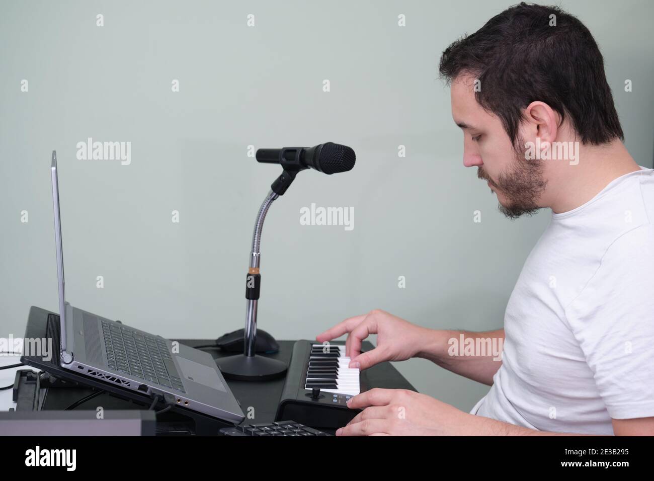 Un homme blogueur, youtuber, influenceur enregistrant une vidéo jouant le piano électronique à la maison. Musicien, chanteur, pianiste. Banque D'Images