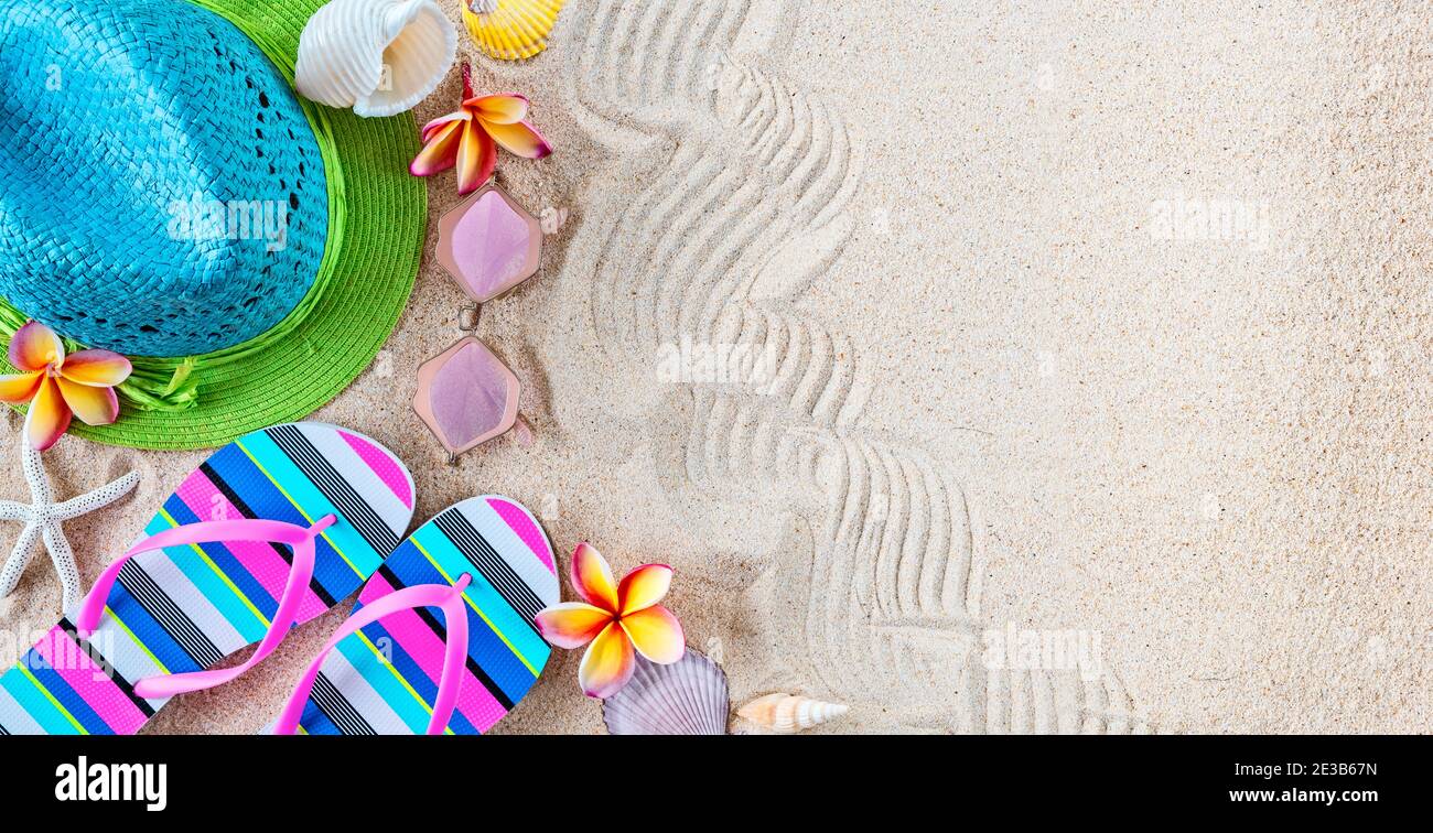 Chapeau de paille bleu et vert et tongs colorées dans le sable avec des coquillages et des fleurs frangipani. Concept d'été sur la plage. Banque D'Images