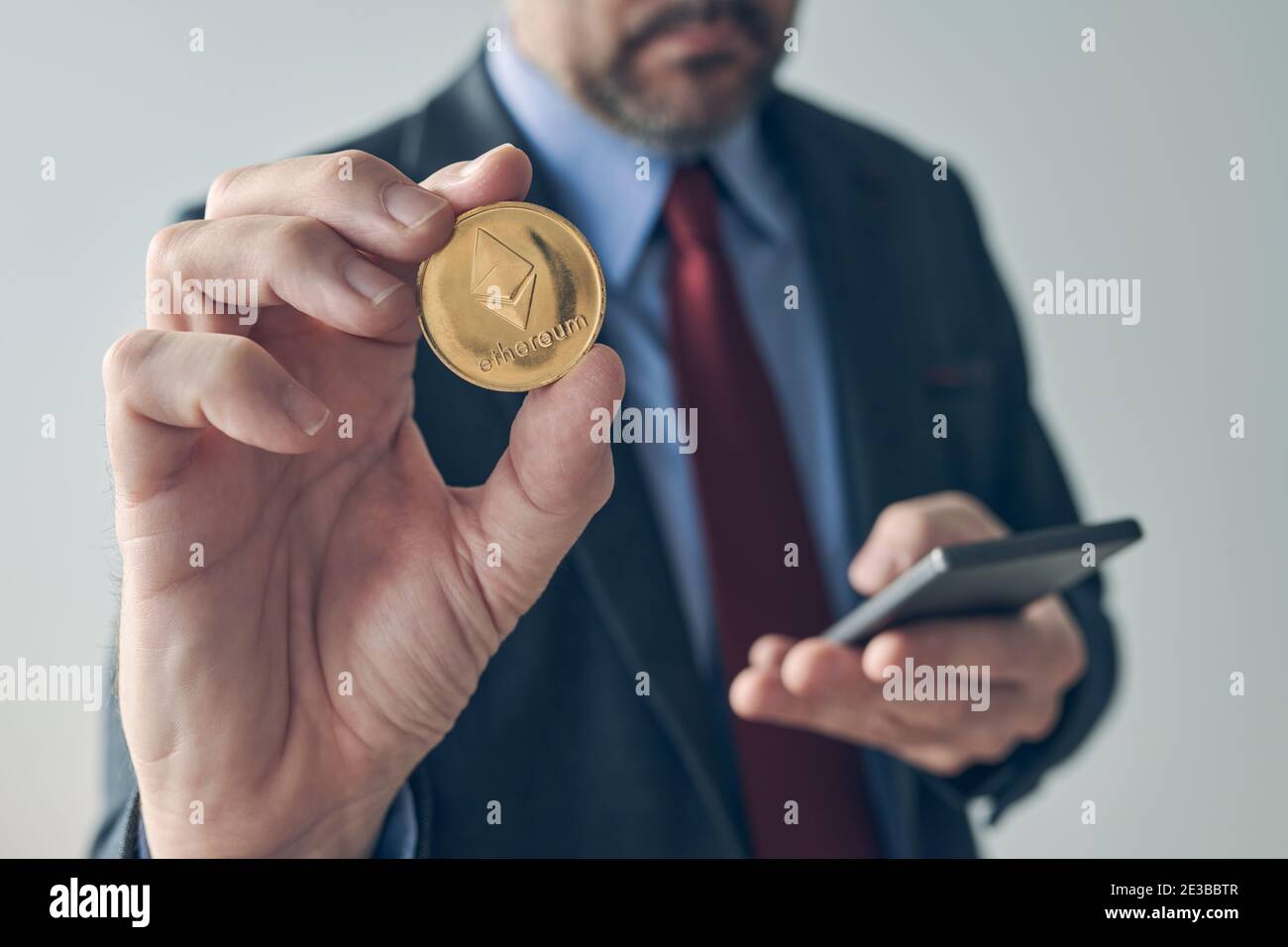 Homme d'affaires utilisant un smartphone pour échanger l'image conceptuelle d'un portefeuille électronique mobile numérique à crypto-monnaie Ethereum avec une attention sélective Banque D'Images