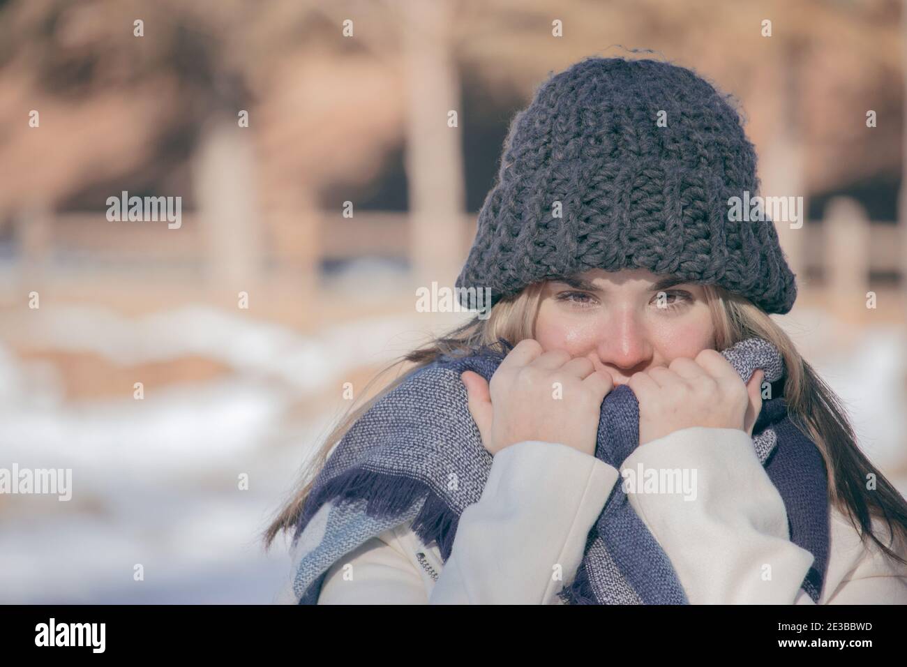 Portrait horizontal d'hiver de belle fille blonde souriante dans une journée de neige avec un chapeau gris et une longue écharpe. Gros plan beauté photo de l'hiver extérieur 2021. Banque D'Images