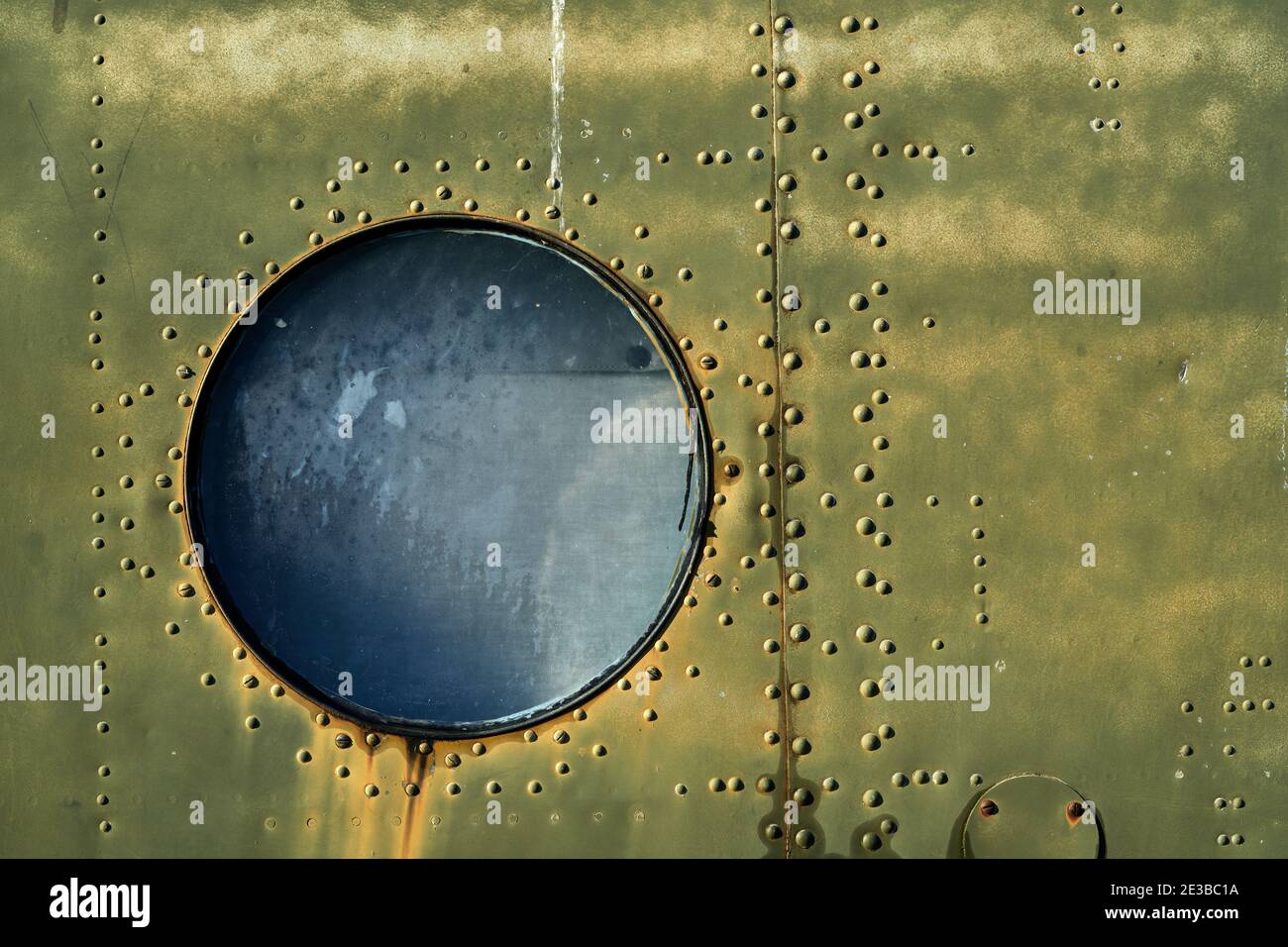 Arrière-plan de l'armée vintage, fenêtre circulaire d'un ancien hélicoptère militaire et surface métallique usée de l'avion Banque D'Images