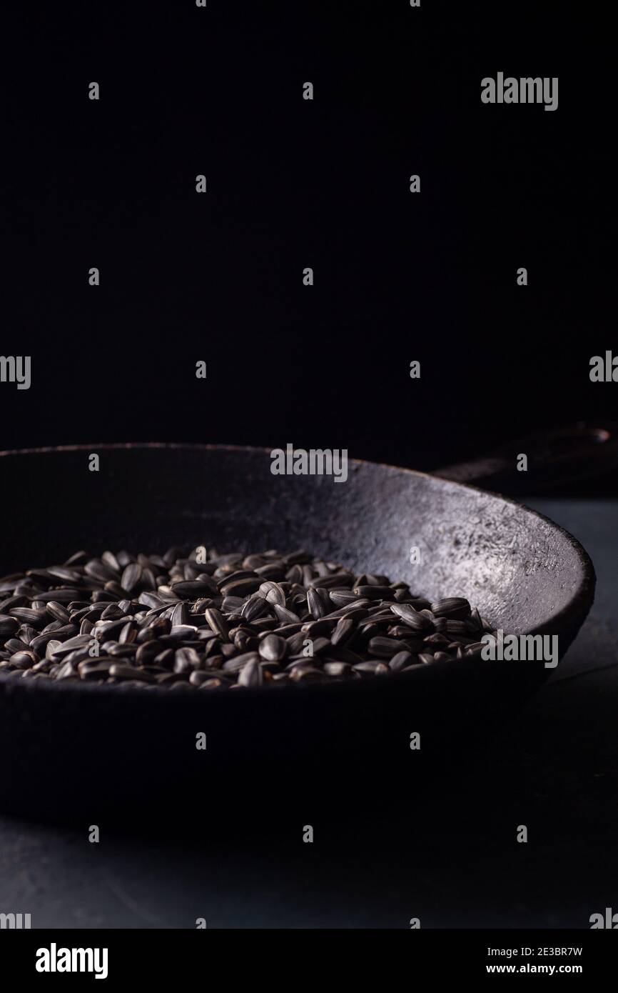 graines de tournesol dans une poêle en fonte noire charrée sur une table en béton gris dans une clé noire, rustique Banque D'Images