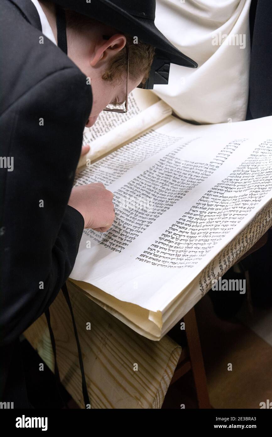Un jeune homme lit à partir de la Mégillah sur le Purim de vacances juives. Dans une synagogue de Crown Heights, Brooklyn, New York Banque D'Images