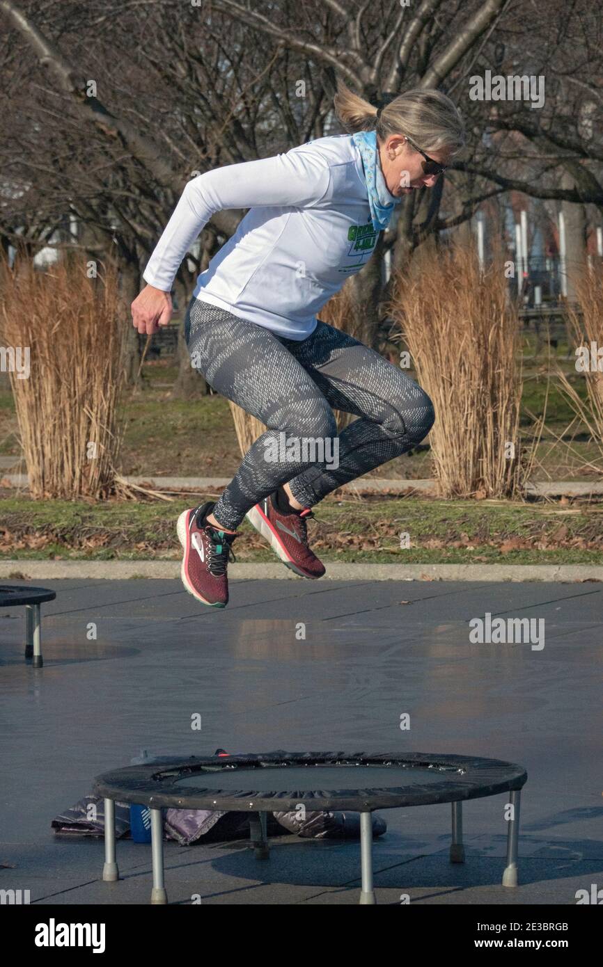 Une femme à une classe de rebondissement qui combine des mouvements vigoureux tout en sautant sur un petit trampoline. Dans le parc Corona de Flushing Meadows à Queens, New York. Banque D'Images