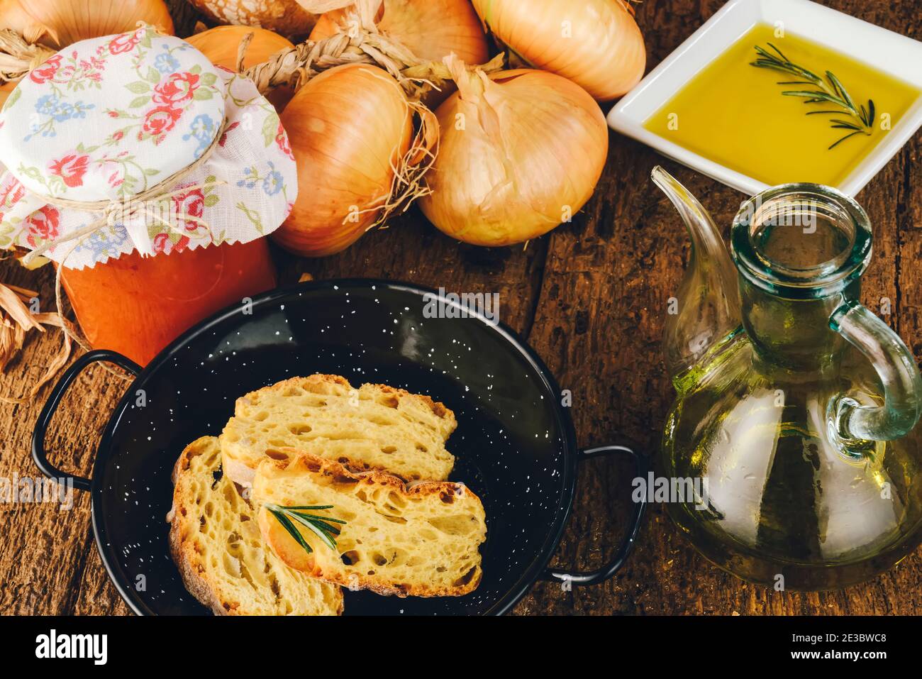 Huile d'olive extra vierge. Pot vintage d'huile d'olive extra vierge aromatisée au romarin dans une cuisine traditionnelle avec du pain, des tomates en conserve, des oignons ... Banque D'Images