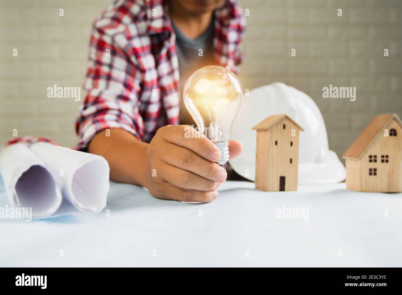 un ingénieur montre une ampoule avec un petit objet de construction et de maison outils sur la table Banque D'Images