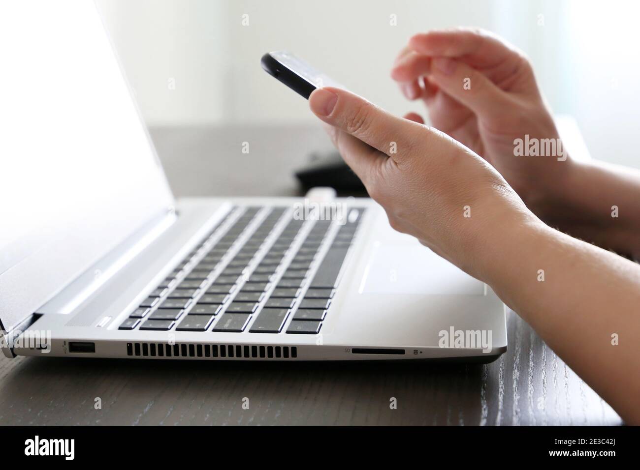 Femme utilisant un smartphone sur l'arrière-plan du clavier de l'ordinateur portable. Concept de communication en ligne, travail au bureau ou à domicile et paiement Banque D'Images