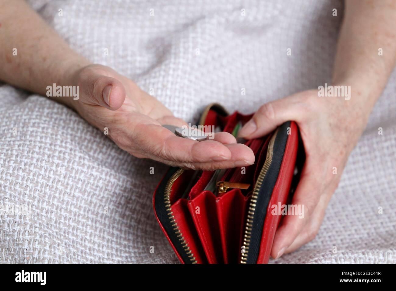 Une femme âgée prend une pièce de son portefeuille, froissée les mains de la femme en gros plan. Concept de pauvreté, paiements de pension, pensionné avec argent métallique Banque D'Images