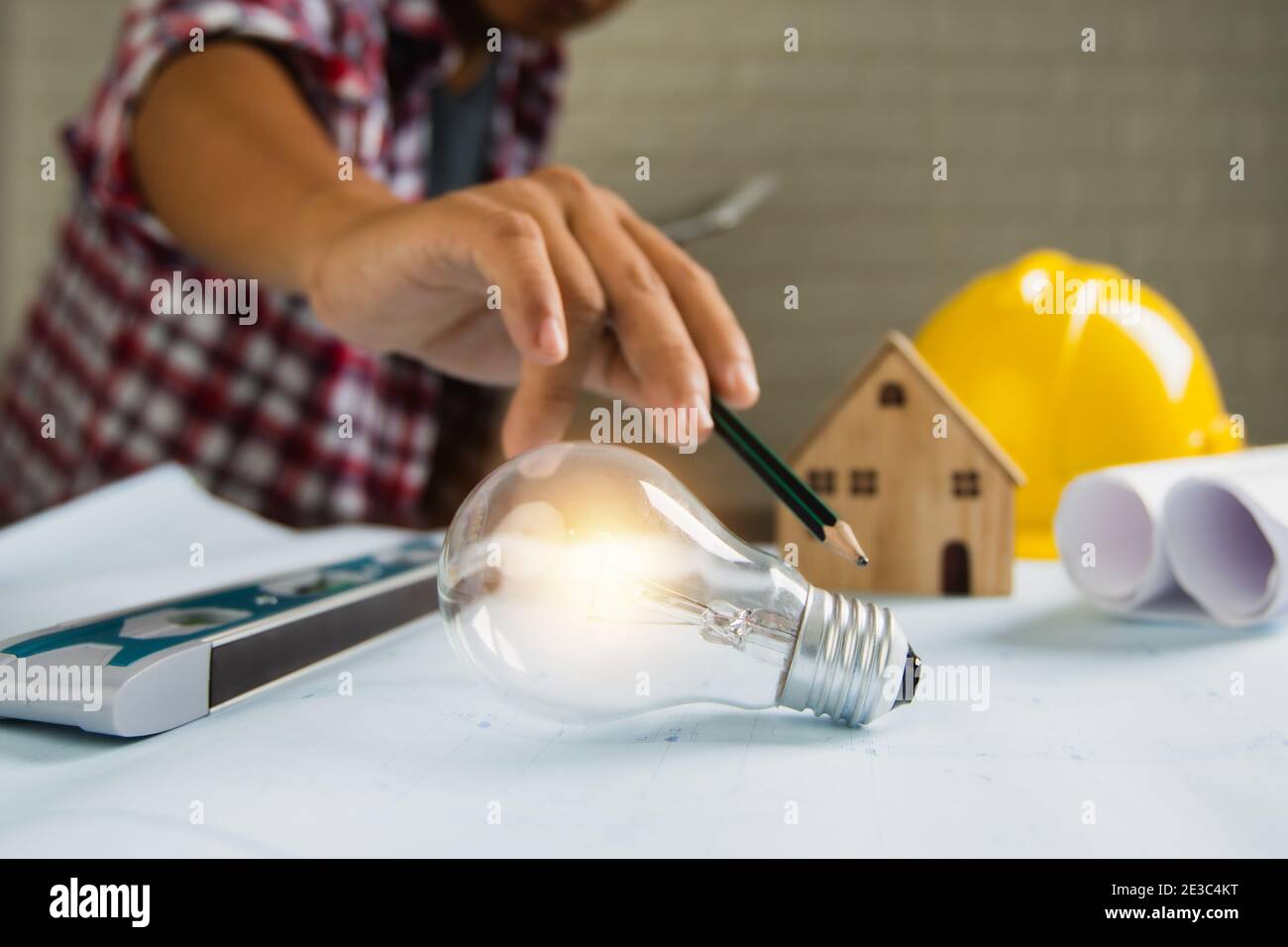 faites un point et montrez l'ampoule avec une petite maison et outils d'objet de construction sur la table Banque D'Images