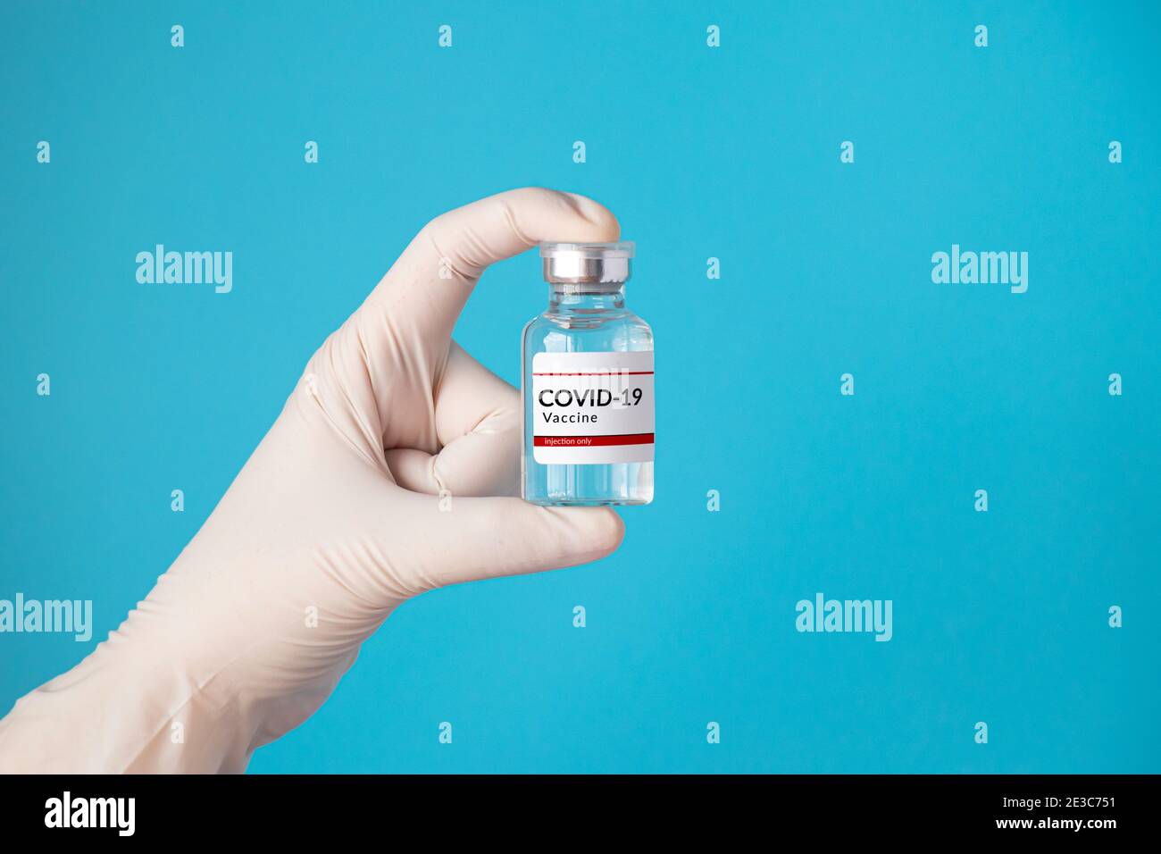 Vaccin coronavirus COVID-19 et concept d'immunisation. Main dans un gant blanc contenant un flacon de vaccin pour injection isolé sur fond bleu Banque D'Images