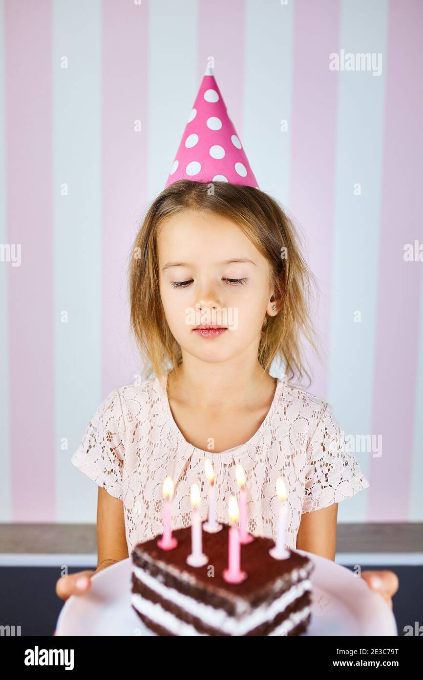 Petite fille en chapeau d'anniversaire rose avec gâteau d'anniversaire au  chocolat et bougies. L'enfant fête son anniversaire. Joyeux anniversaire  Photo Stock - Alamy