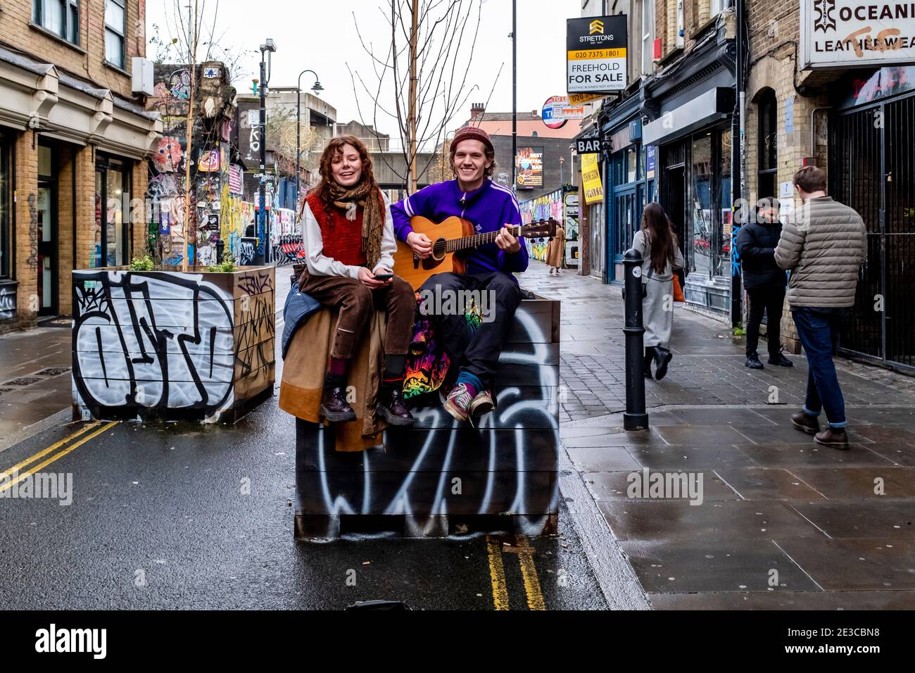 Un jeune couple Busking à Brick Lane, Londres, Royaume-Uni. Banque D'Images