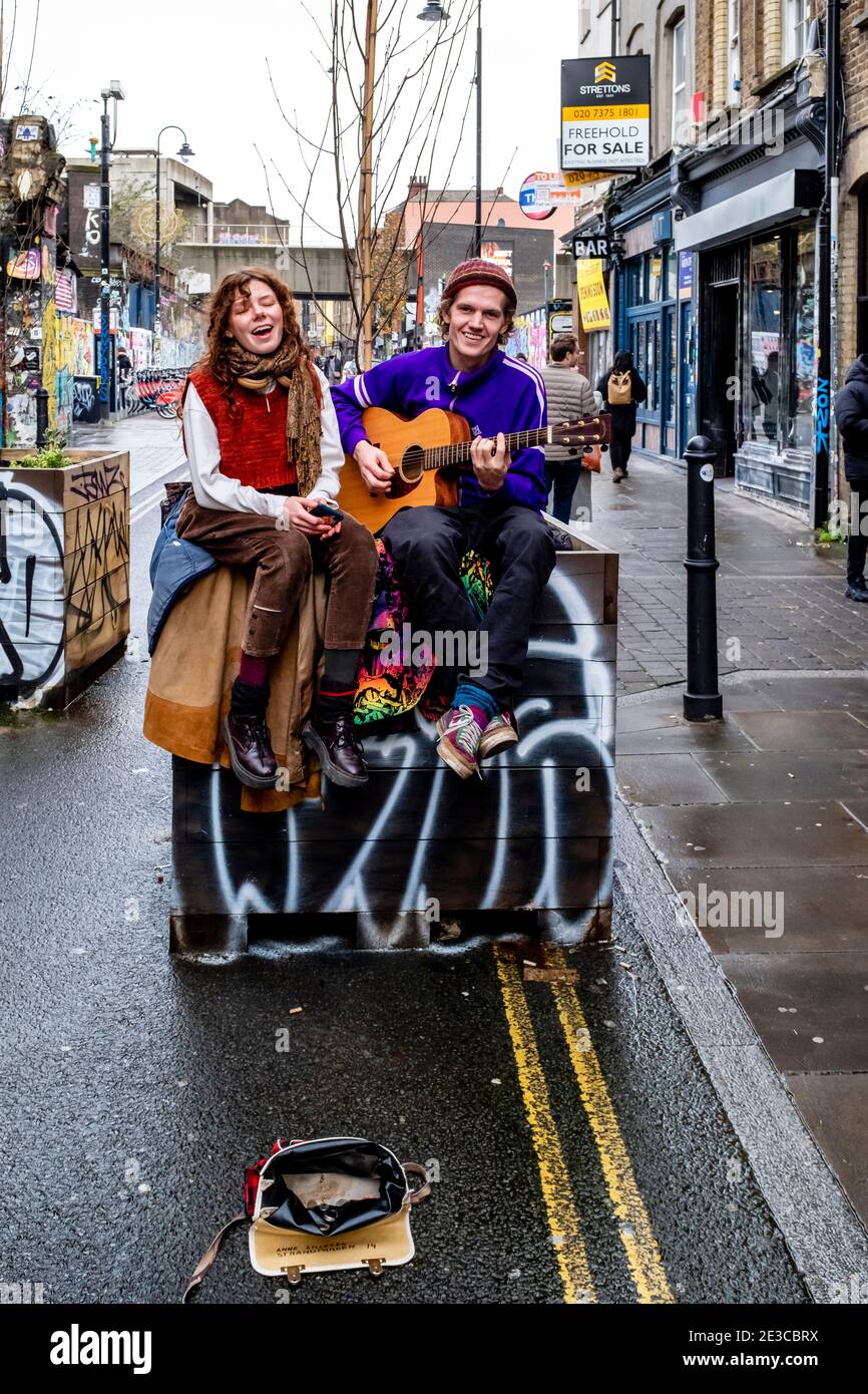 Un jeune couple Busking à Brick Lane, Londres, Royaume-Uni. Banque D'Images