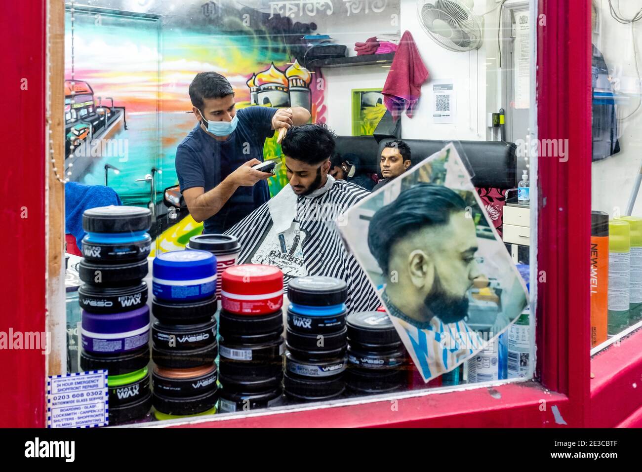 Un jeune homme a UNE coupe de cheveux dans UN salon de coiffure de Brick Lane, Londres, Royaume-Uni. Banque D'Images