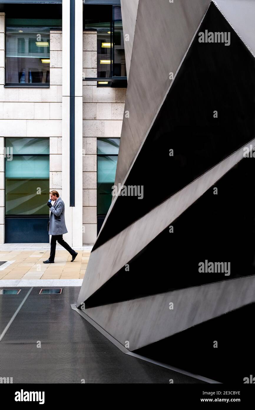 Un jeune homme buvant du café passe devant les évents Paternoster, Londres, Royaume-Uni. Banque D'Images