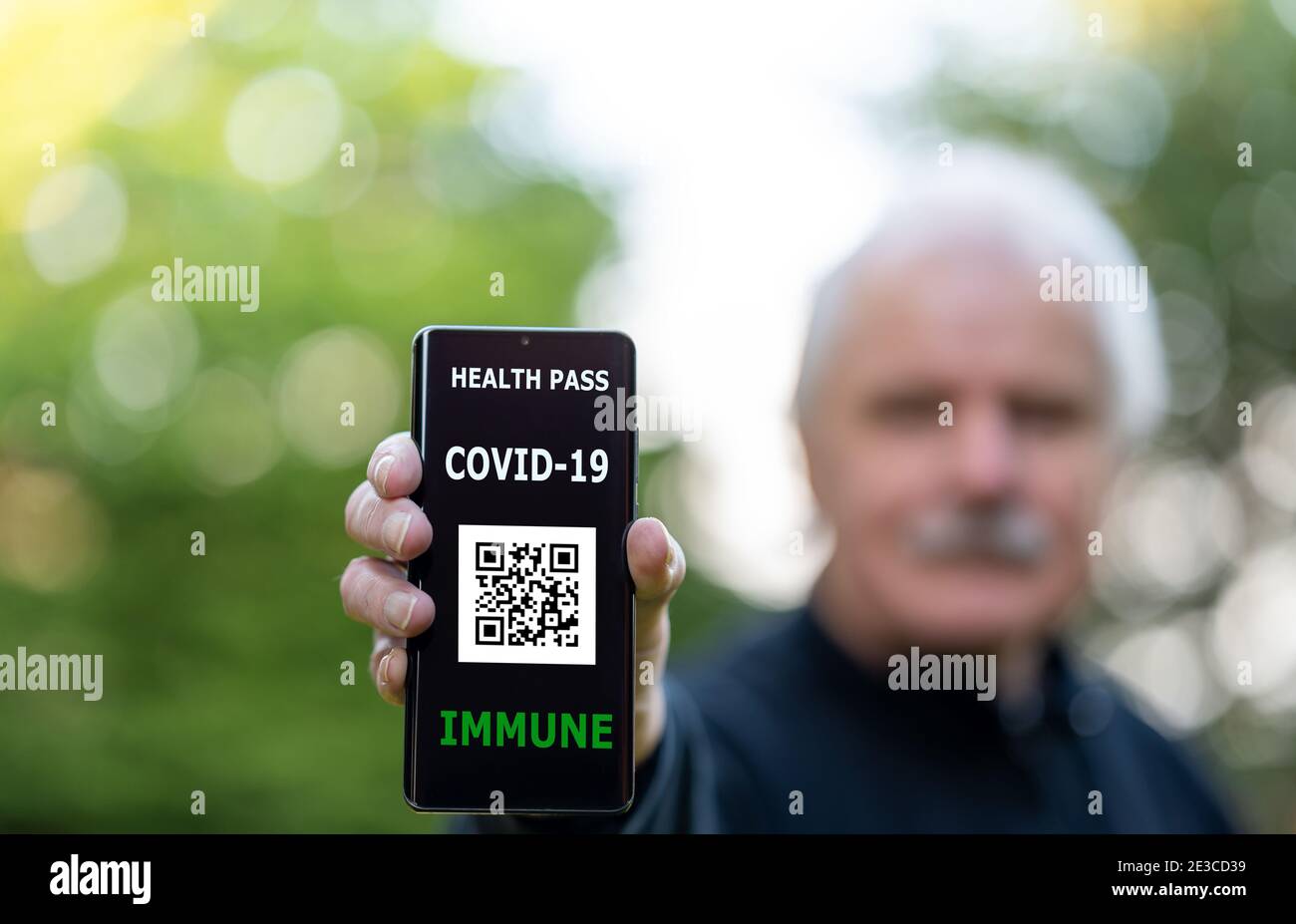 Homme âgé présentant un certificat de vaccination sur un téléphone portable, qui indique une vaccination contre le covid-19. Banque D'Images