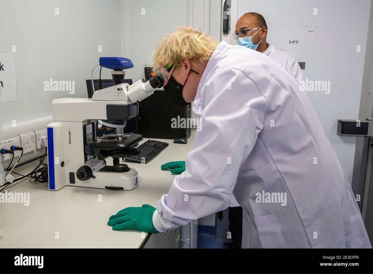 Le Premier ministre Boris Johnson examine un microscope dans le laboratoire de contrôle de la qualité, où des lots de vaccins sont testés, lors d'une visite de l'usine de fabrication du vaccin Oxford/AstraZeneca à Oxford Biomedica dans l'Oxfordshire. Date de la photo: Lundi 18 janvier 2021. Banque D'Images