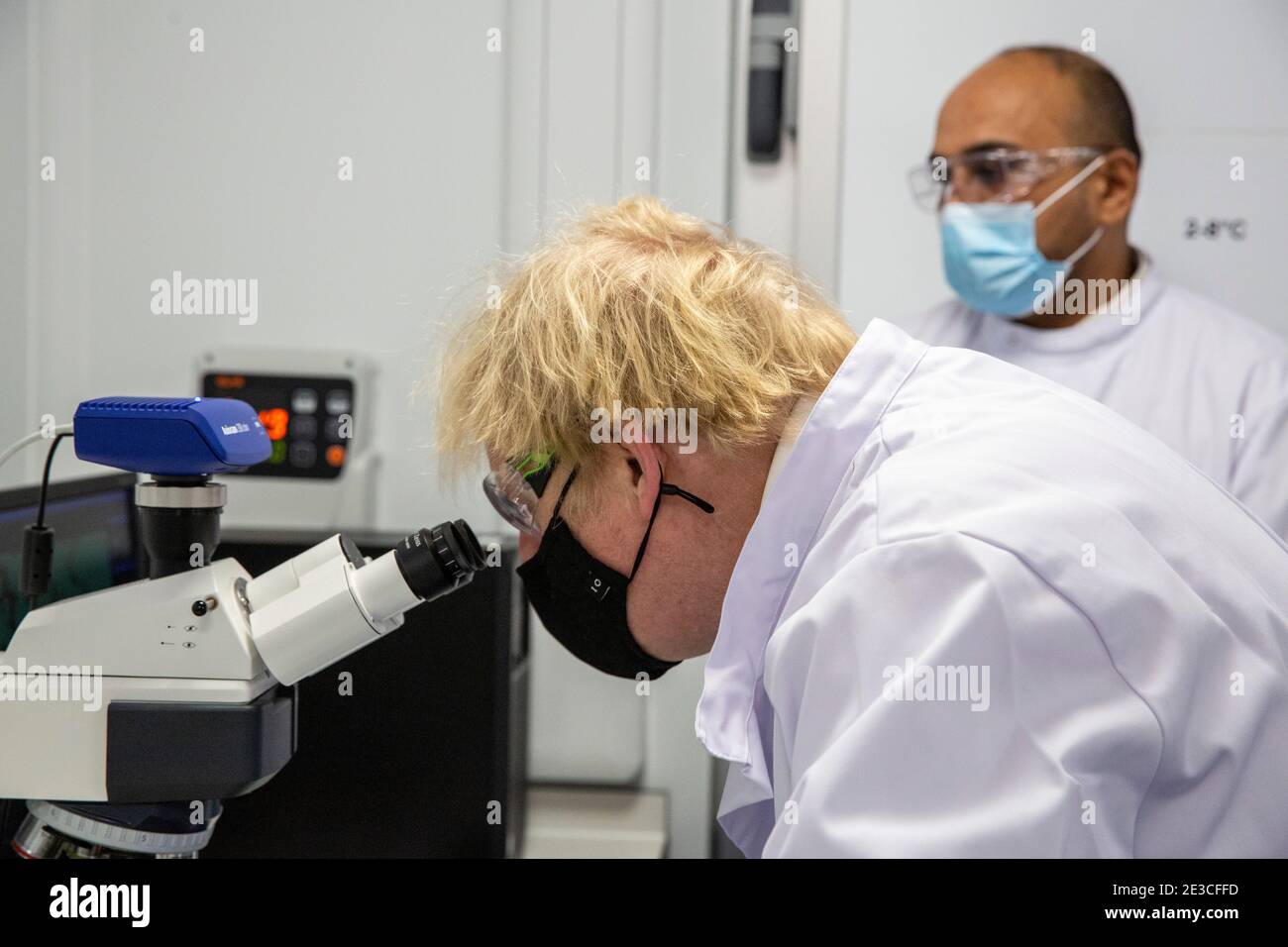Le Premier ministre Boris Johnson examine un microscope dans le laboratoire de contrôle de la qualité, où des lots de vaccins sont testés, lors d'une visite de l'usine de fabrication du vaccin Oxford/AstraZeneca à Oxford Biomedica dans l'Oxfordshire. Date de la photo: Lundi 18 janvier 2021. Banque D'Images