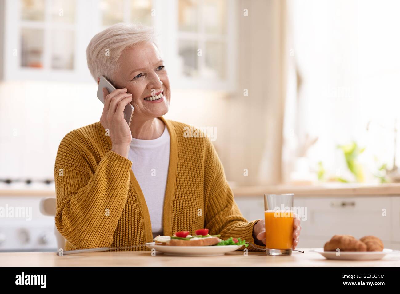 Bonne femme âgée, déjeuner et parler au téléphone Banque D'Images