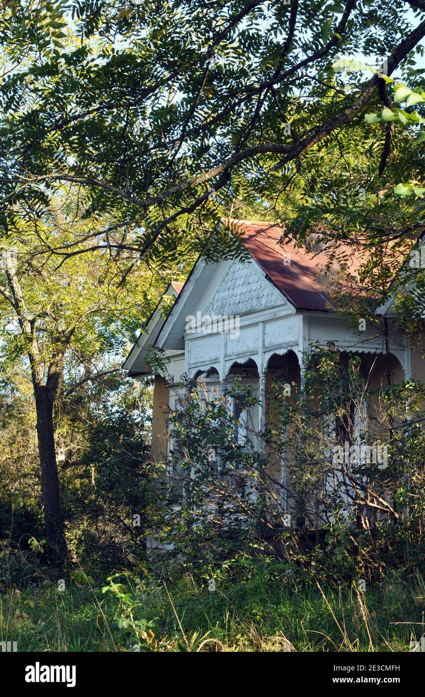 Une vieille maison avec des boiseries détaillées est cachée par des arbres et des arbustes près de Hazelgreen, Missouri. Banque D'Images