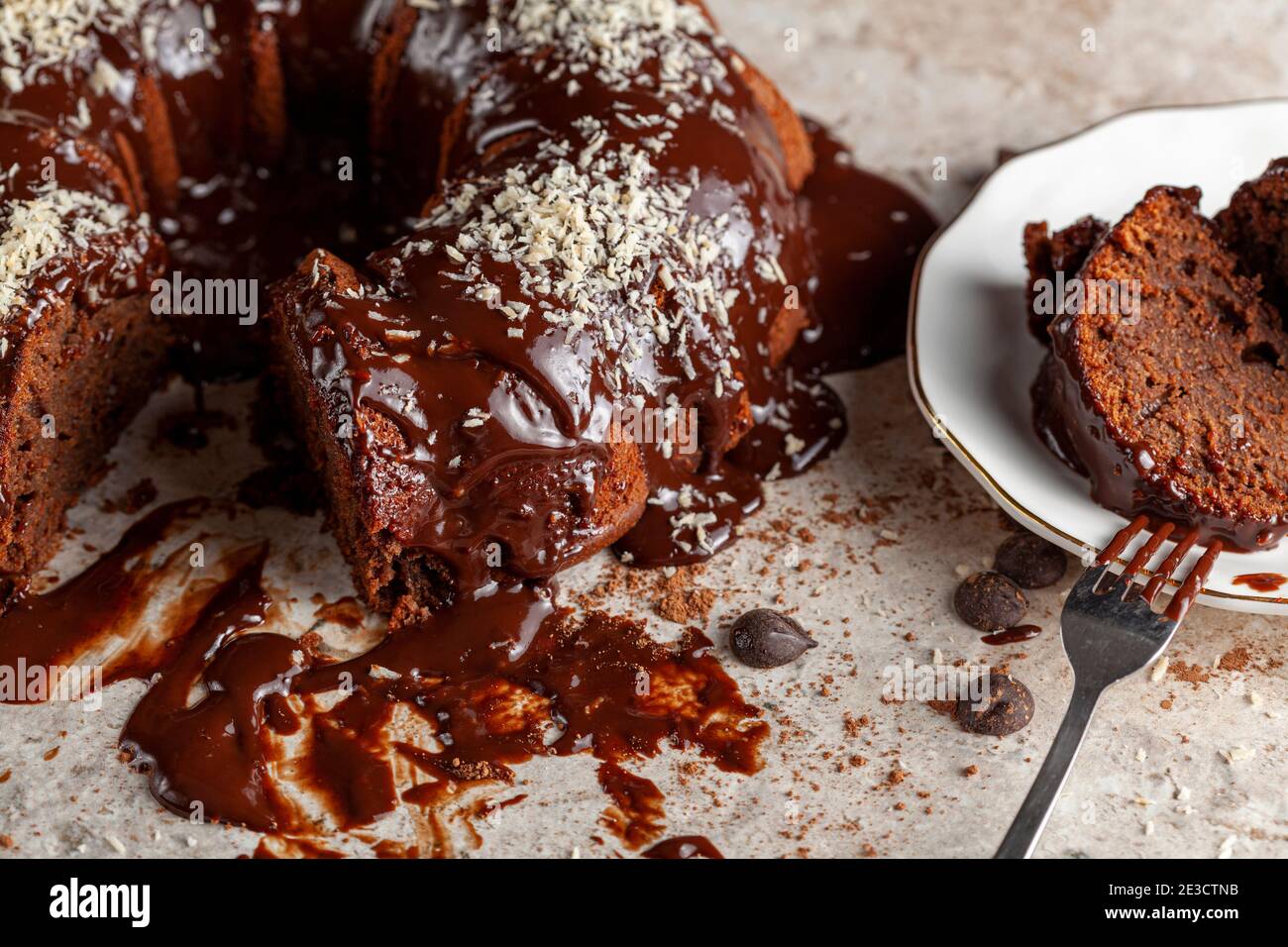 Vue Laterale Inclinee D Un Gateau Au Chocolat Rond Gastronomique Avec Des Noix De Coco Ralees Sur La Glace Deux Tranches Ont Ete Retirees Et Placees Sur Une Plaque En Porcelaine Blanche Avec