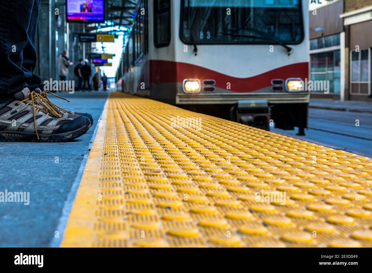 Veuillez vous tenir derrière la ligne jaune, une vue au niveau du sol de, un homme se tient les orteils à la ligne jaune à l'approche d'un train de banlieue local. Banque D'Images