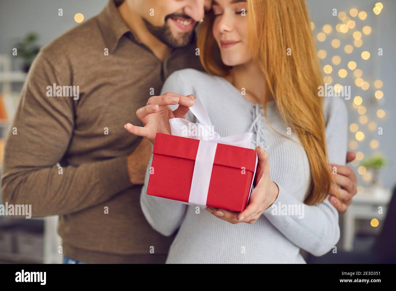 Belle femme aimante jeune couple et homme embrassant et tenant coffret cadeau de noël rouge avec cadeau Banque D'Images