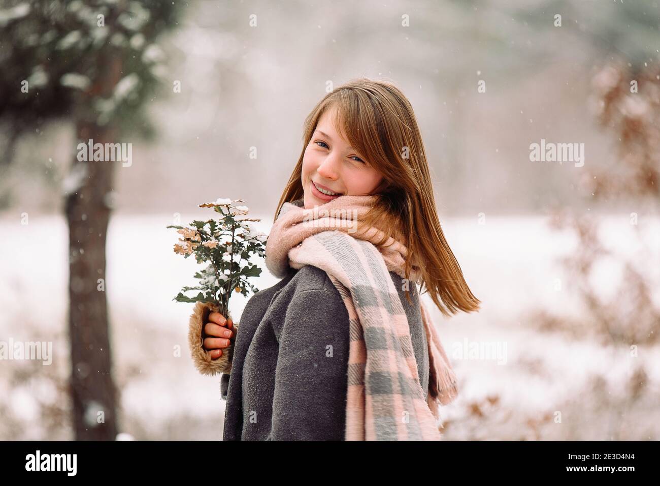 Portrait d'une jolie fille enveloppée de froid une écharpe chaude portant  un bouquet avec un smiley looks à l'appareil photo contre l'arrière-plan  d'un Photo Stock - Alamy