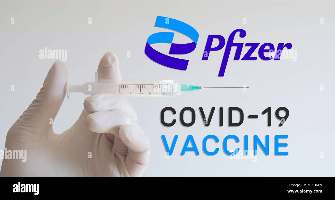 Main avec gant tient la seringue à côté du logo de Pfizer, l'une des sociétés développant un vaccin Covid-19 (coronavirus). Vienne, Autriche - 18 janvier 202 Banque D'Images