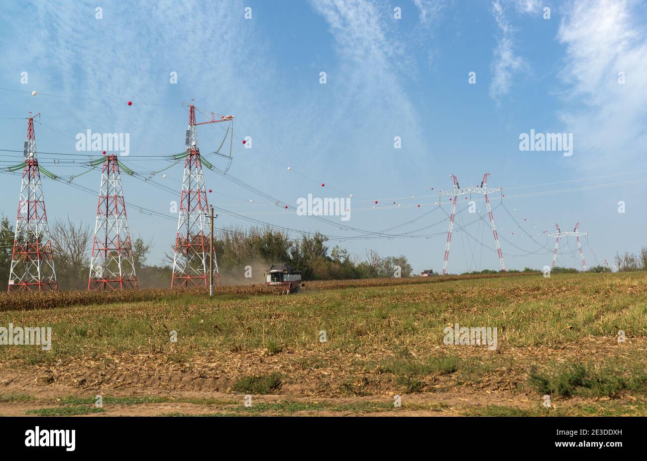Sur le terrain avec une ligne haute puissance va la machine de récolte. Utilisation rationnelle de la terre Banque D'Images
