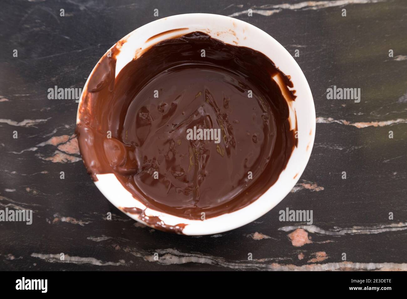 Chocolat chaud fondu dans un bol en plastique blanc. Gros plan. Banque D'Images