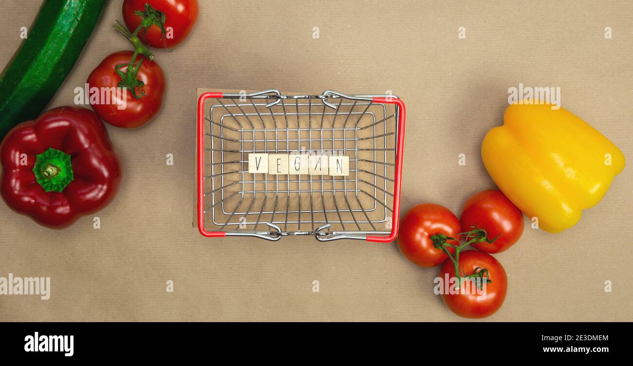 Vegan écrit sur des cubes en bois entouré de légumes dans panier d'achats vue du dessus avec papier de fond de métier, Vega, nourriture saine, végétarien Banque D'Images