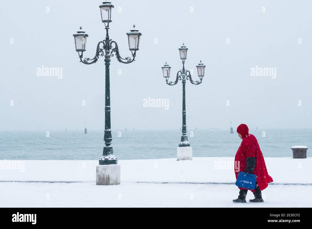 Venise - Riva dei Sette Martiri. Donna à mantello rosso cammina sotto la neve. Venise - une femme marche sous la tempête de neige sur la Riva dei Sette Marti Banque D'Images