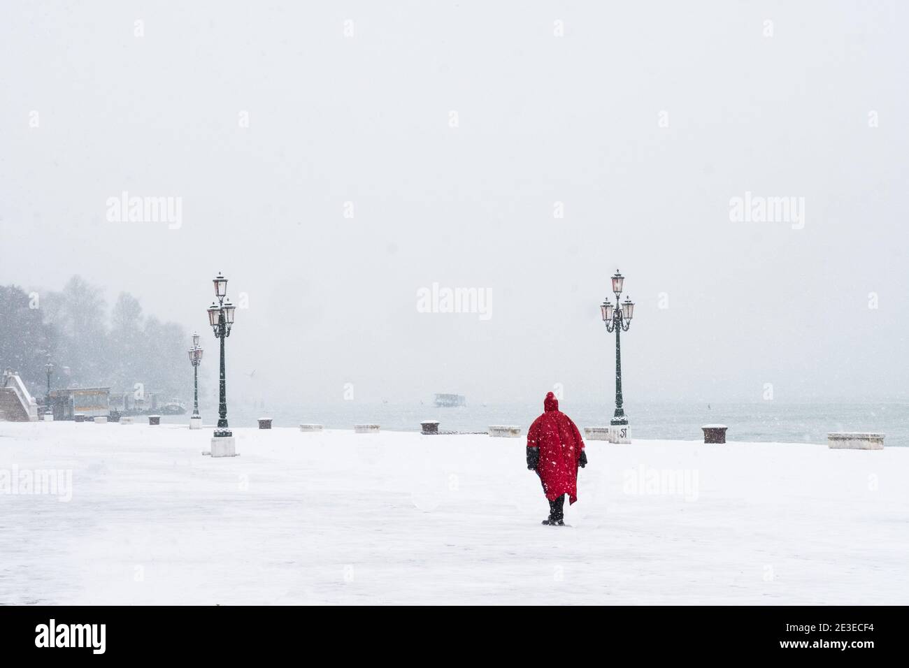 Venise - Riva dei Sette Martiri. Donna à mantello rosso cammina sotto la neve. Venise - une femme marche sous la tempête de neige sur la Riva dei Sette Martir Banque D'Images