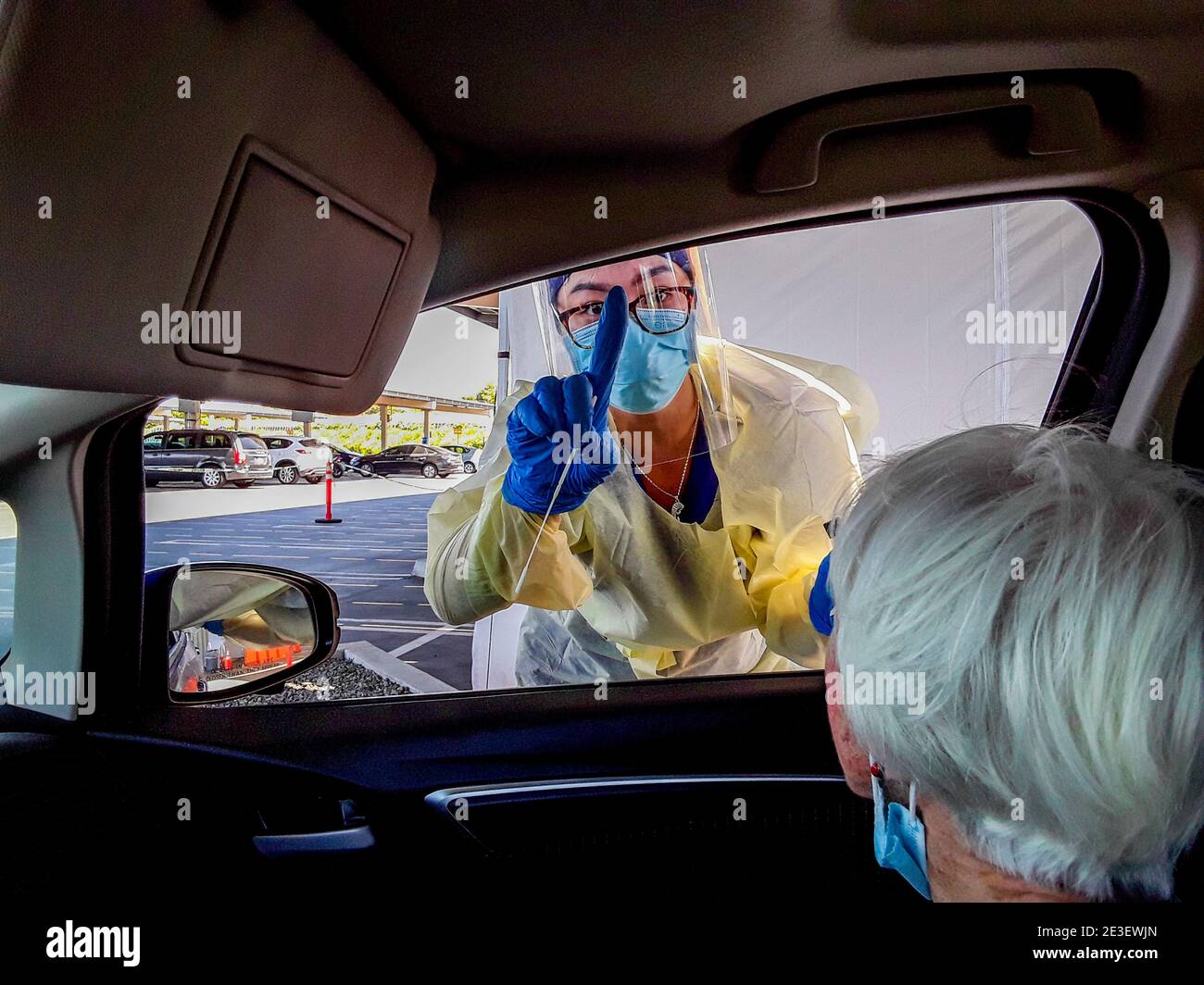 Un technicien médical hispanique en masque de sécurité et gants en caoutchouc Se prépare à administrer un test COVID-19 sur un lecteur Patient dans un califor méridional Banque D'Images
