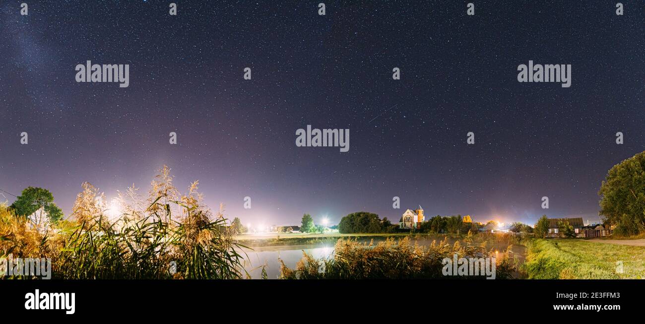 Panorama de l'évaporation sur le lac de la rivière près de Maisons dans le village. Ciel étoilé de nuit au-dessus de la rivière Lake avec étoiles brillantes et piste météorique. Brillant Banque D'Images