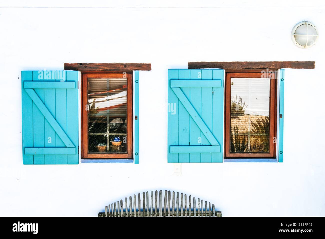 Façade blanche avec deux fenêtres en bois et volets turquoise Banque D'Images