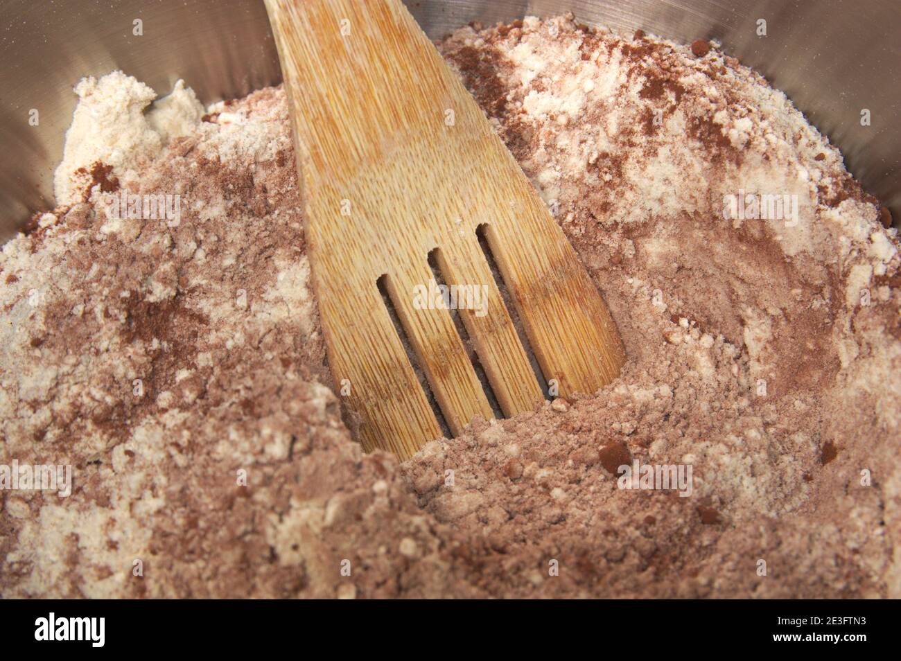 Une palette en bois avec laquelle le mélange de farine et le cacao est fait dans un bol pour faire un gâteau ou sucré maison Banque D'Images