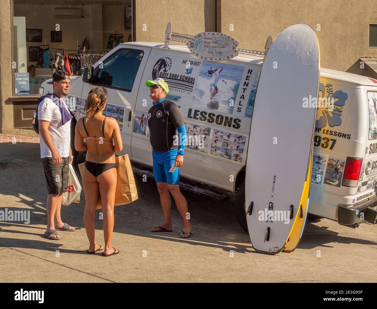 Un jeune couple se converse avec un professeur de surf professionnel à Laguna Beach, CA. Banque D'Images