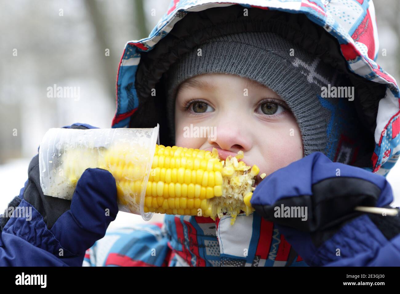 Enfant mangeant du maïs dans le parc de printemps Banque D'Images