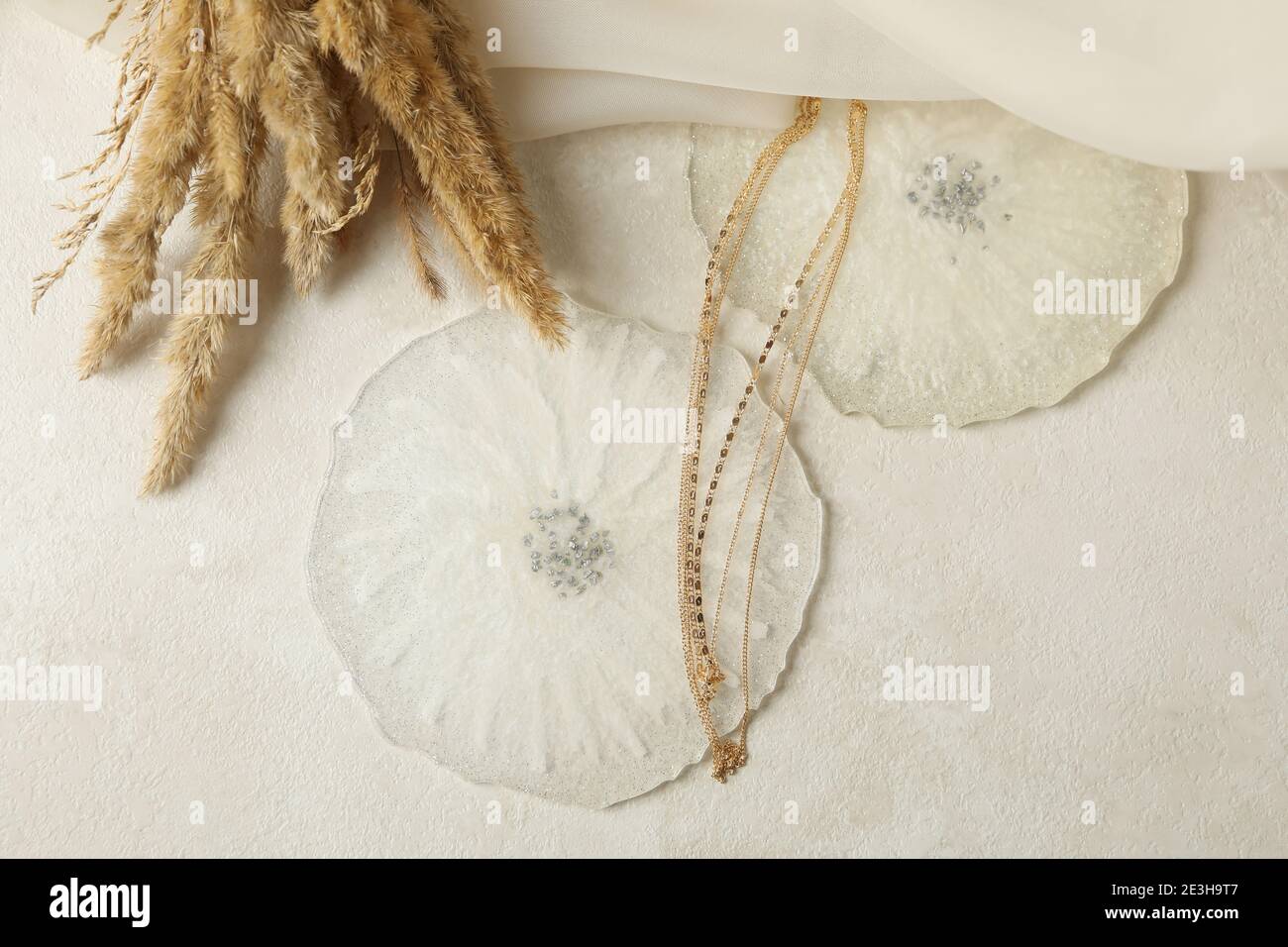 Résine époxy, tissu, chaîne dorée et fleurs de champ sur fond blanc Banque D'Images