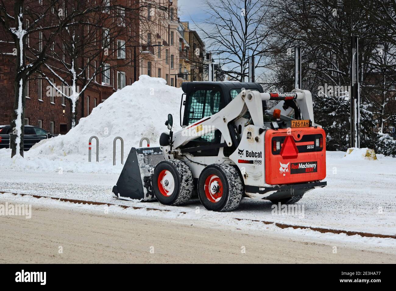 Mini-chargeuse Bobcat S650 pour enlever la neige en stationnement sur le côté de la rue de la ville. Helsinki, Finlande. 18 janvier 2021. Banque D'Images