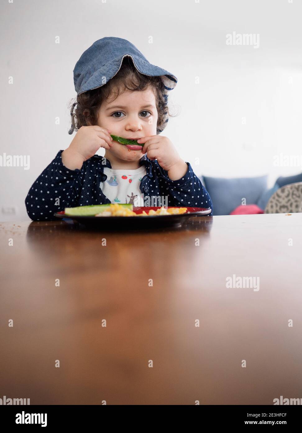 Jeune enfant assis à une table mangeant avec ses mains Banque D'Images