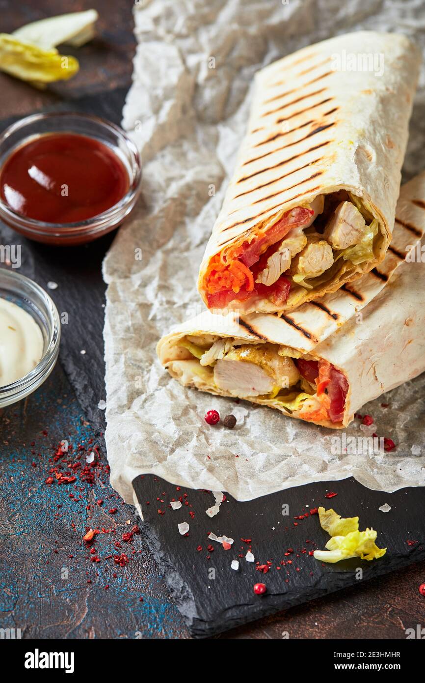 Shawarma traditionnel de l'est avec poulet et légumes, donner Kebab avec sauces sur ardoise. Restauration rapide. Cuisine de l'est. Banque D'Images