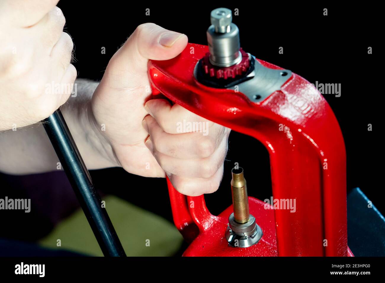 Pression manuelle rouge et coque ammo sur fond sombre, mise au point douce. Copier l'espace. Processus de fabrication d'une cartouche de fusil Banque D'Images