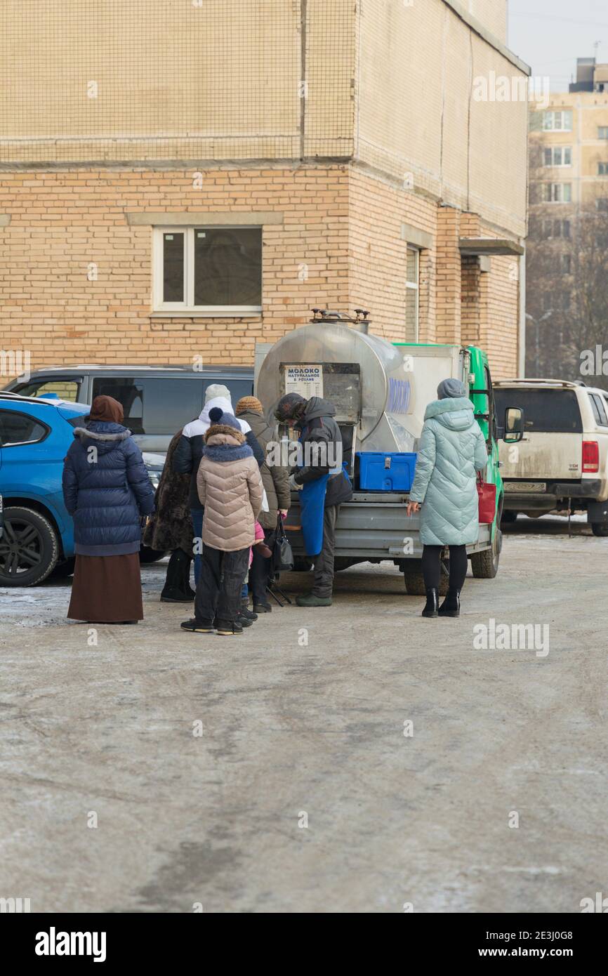 Saint-Pétersbourg, Russie - 09 janvier 2021: File d'attente composée de femmes signifie lait de ferme dans une citerne dans la cour d'un quartier résidentiel ver Banque D'Images