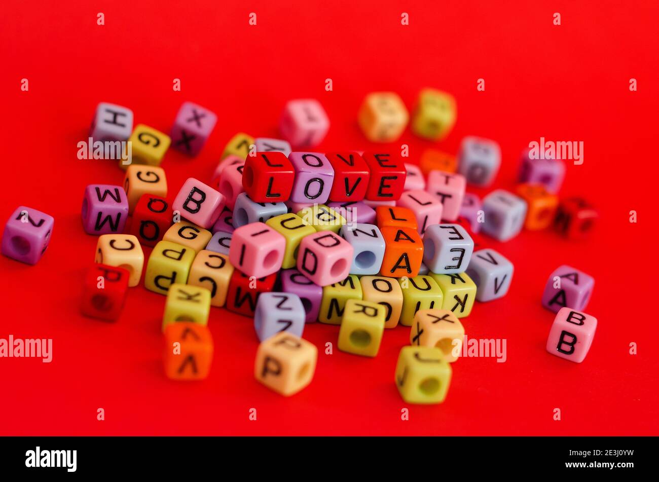 Perles de cube en bois colorées avec lettres sur fond rouge festif, mot « Love ». Saint Valentin. 14 février. Flat lay, vue de dessus. Banque D'Images