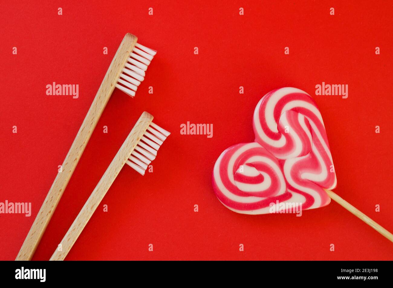 Fond rouge festif. Bonbons en forme de cœur doux. Et deux brosses à dents comme un symbole de l'amour. Saint Valentin. 14 février. Idées de cadeaux. Plat la Banque D'Images