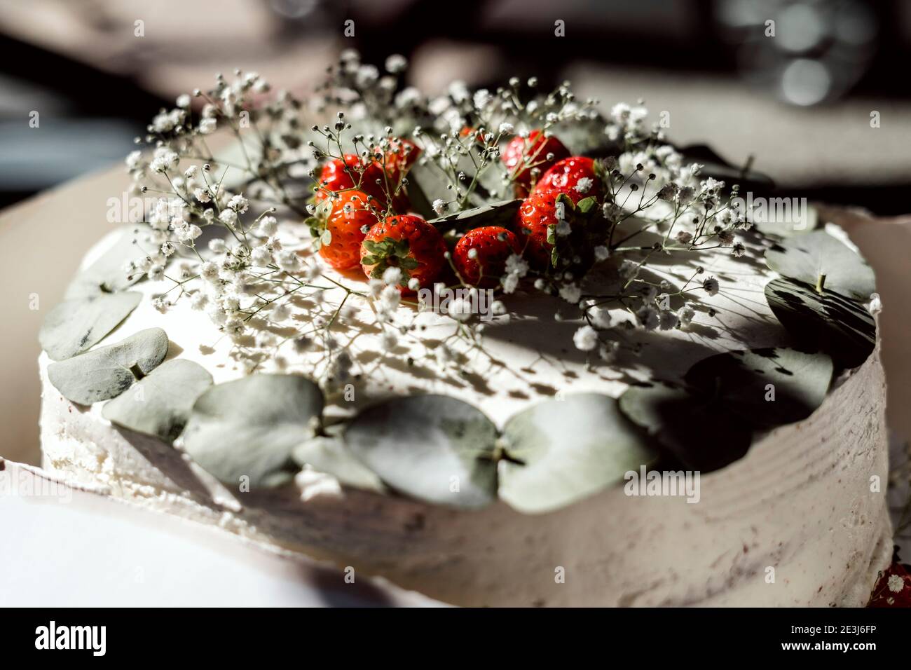 Gros plan d'un gâteau de mariage rustique décoré de tsisophila et fraises Banque D'Images